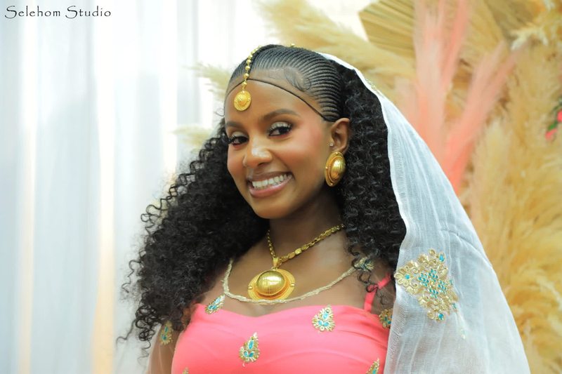 Bride smiling in a white veil and pink dress