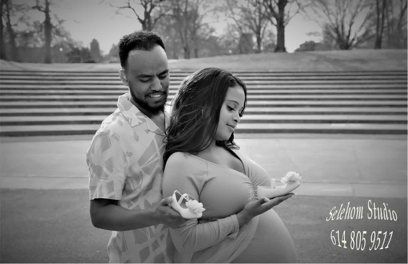 Expectant couple embracing outdoors in a black-and-white portrait