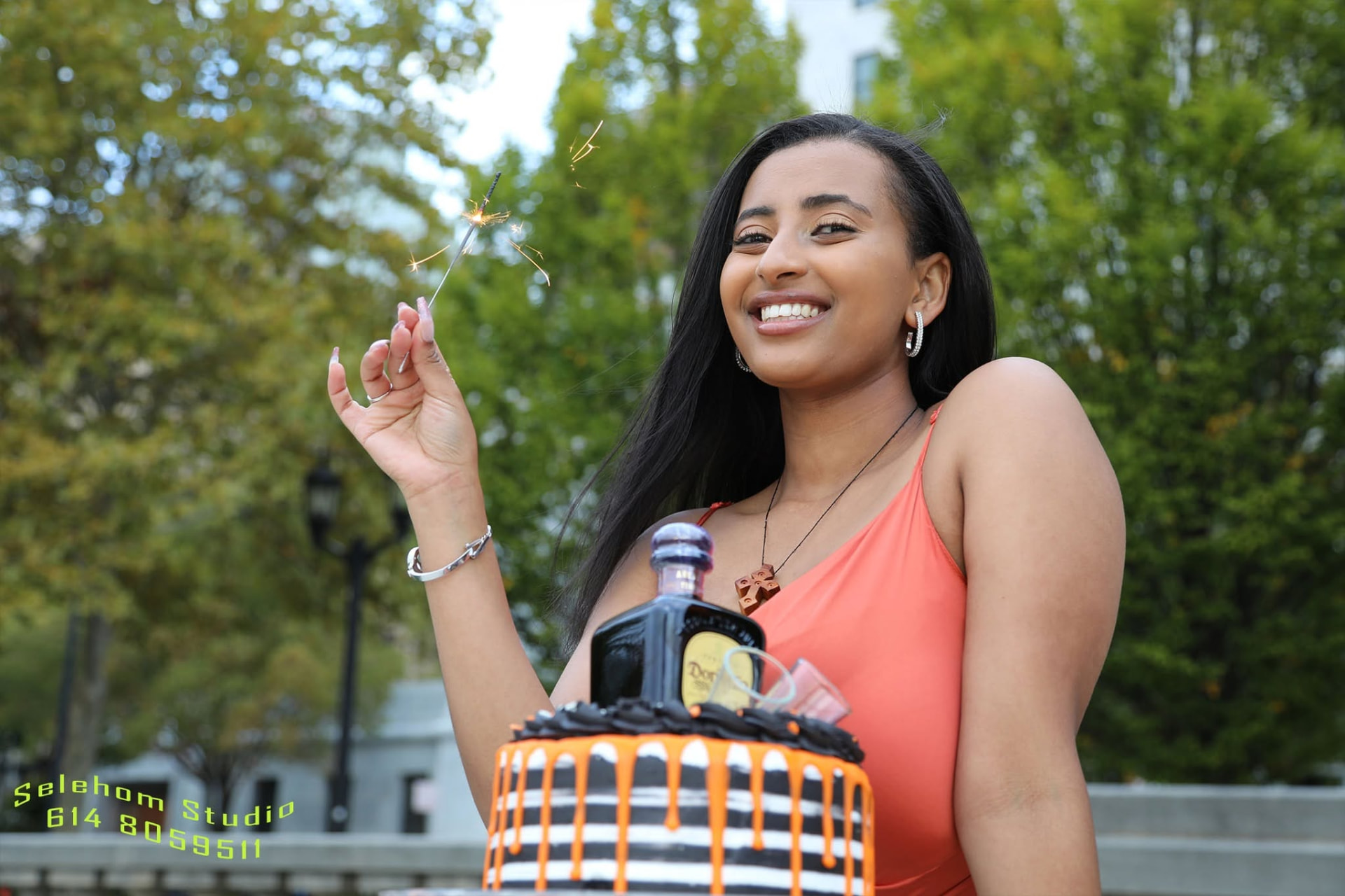 Woman holding a sparkler behind a birthday cake outdoors